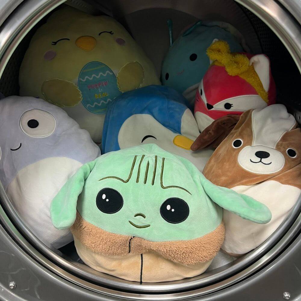 Squishmallows peering out of the dryer